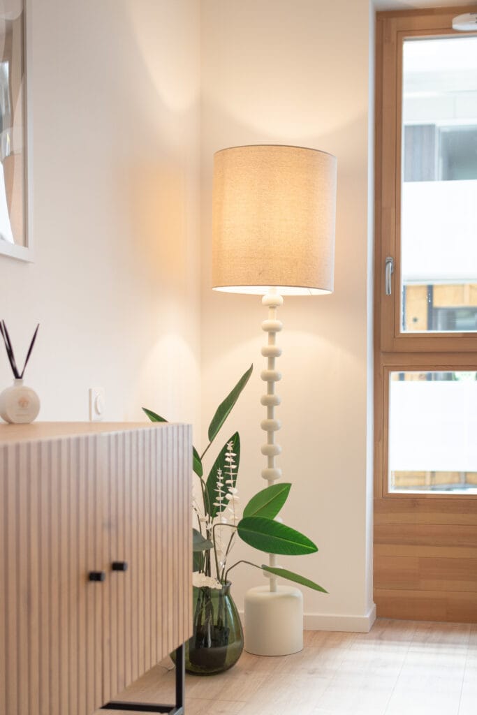 Détail d’un intérieur d’appartement photographié à Nancy, avec lampe, plante et fenêtre en bois